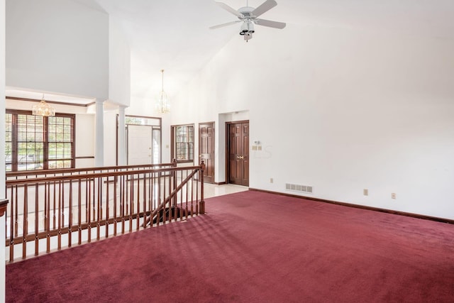 unfurnished room with ceiling fan with notable chandelier, light colored carpet, and high vaulted ceiling