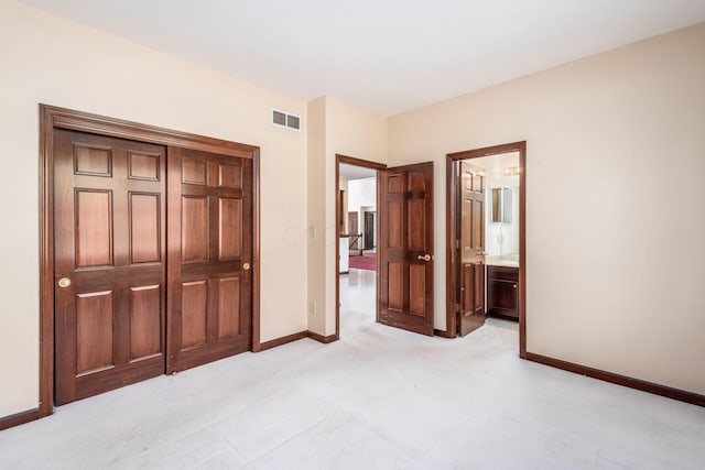 unfurnished bedroom featuring light carpet and ensuite bath