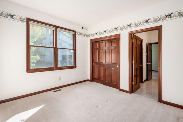 unfurnished bedroom featuring light carpet and a closet