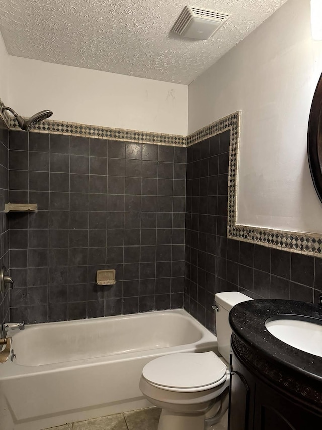 full bathroom featuring tile walls, vanity, a textured ceiling, and tiled shower / bath