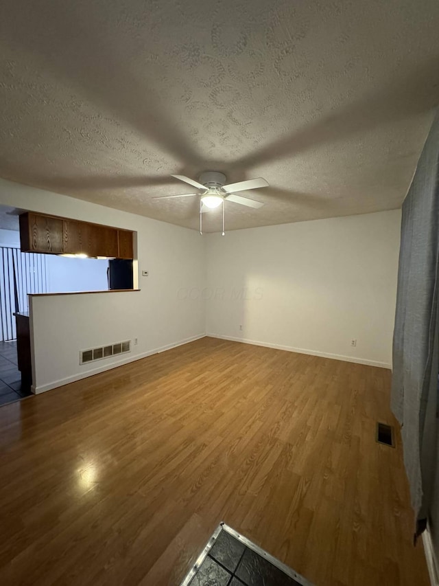 unfurnished living room featuring hardwood / wood-style flooring, ceiling fan, and a textured ceiling