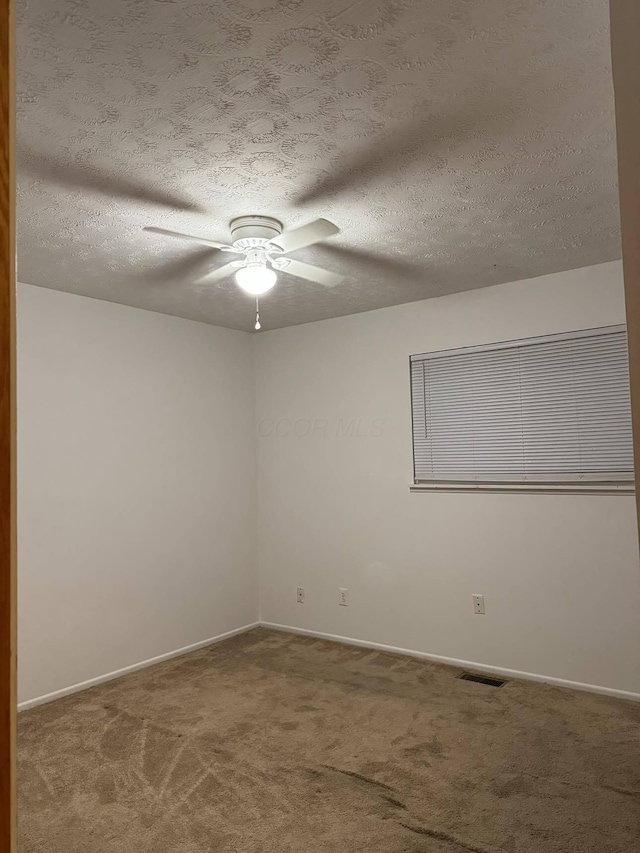 empty room with ceiling fan, carpet, and a textured ceiling