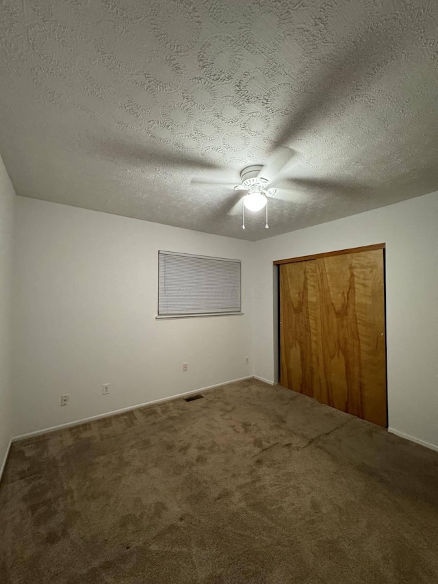 unfurnished bedroom featuring carpet flooring, ceiling fan, a textured ceiling, and a closet