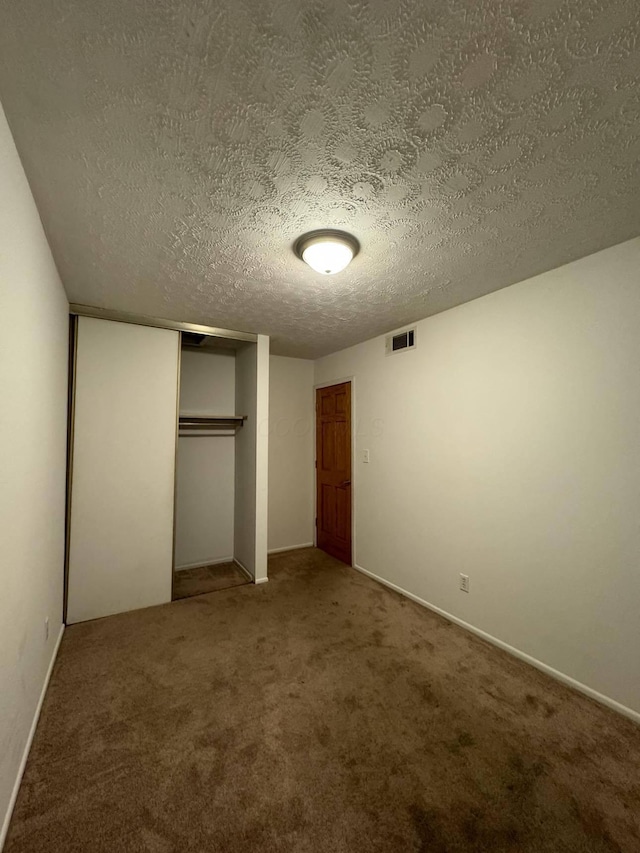 unfurnished bedroom with carpet flooring, a closet, and a textured ceiling