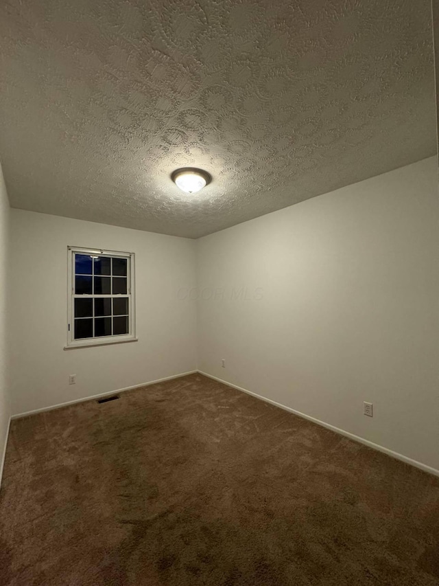 spare room featuring carpet and a textured ceiling