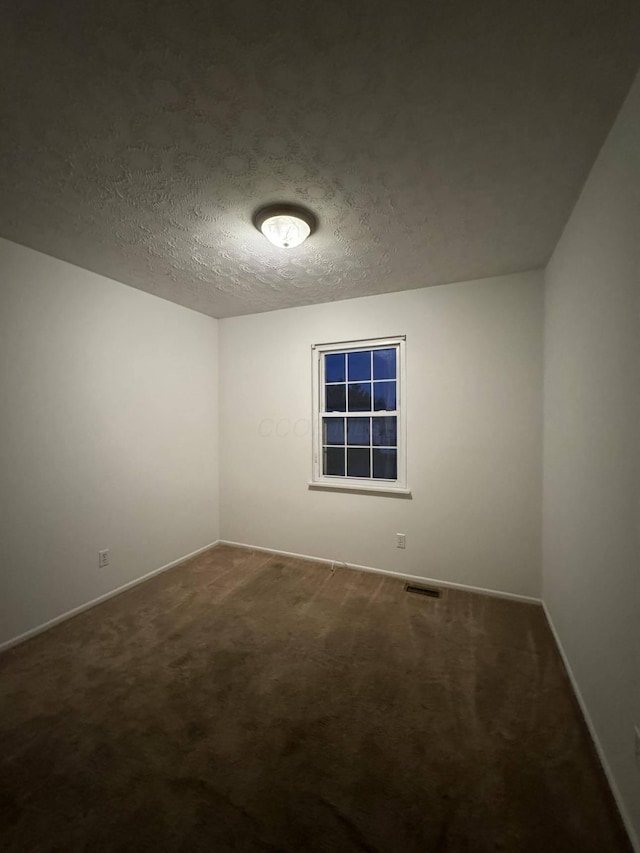 carpeted empty room featuring a textured ceiling