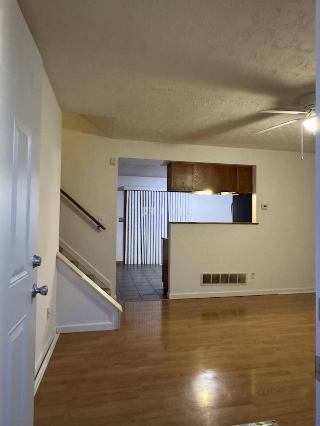 interior space featuring ceiling fan, dark wood-type flooring, and a textured ceiling