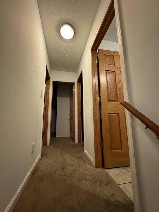 hall featuring light carpet and a textured ceiling