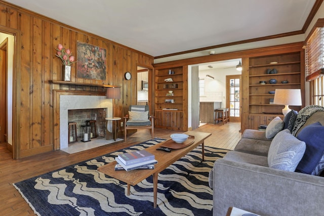 living room with built in features, a high end fireplace, and hardwood / wood-style floors