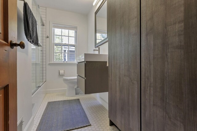 full bathroom with tile patterned flooring, vanity, bath / shower combo with glass door, and toilet