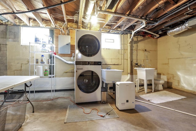 basement featuring sink, stacked washer / dryer, and electric panel