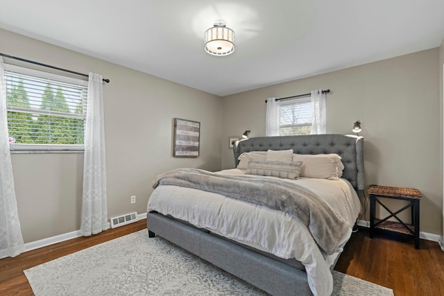 bedroom featuring visible vents, baseboards, and wood finished floors