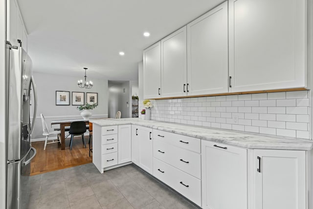kitchen with a chandelier, stainless steel fridge with ice dispenser, white cabinetry, and light tile patterned floors