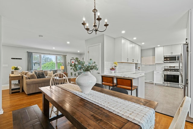 dining room featuring light wood-style floors, an inviting chandelier, baseboards, and recessed lighting