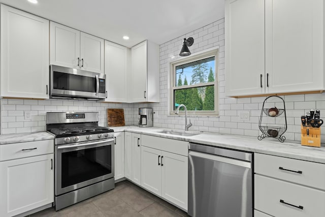 kitchen with a sink, light tile patterned floors, white cabinetry, and stainless steel appliances