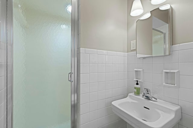full bathroom with a sink, tile walls, and a shower stall