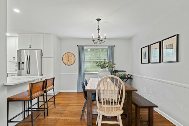 dining room featuring baseboards, a chandelier, and wood finished floors