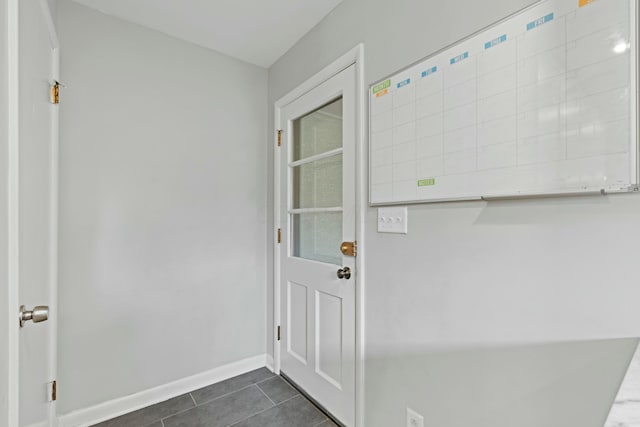 entryway with dark tile patterned flooring and baseboards