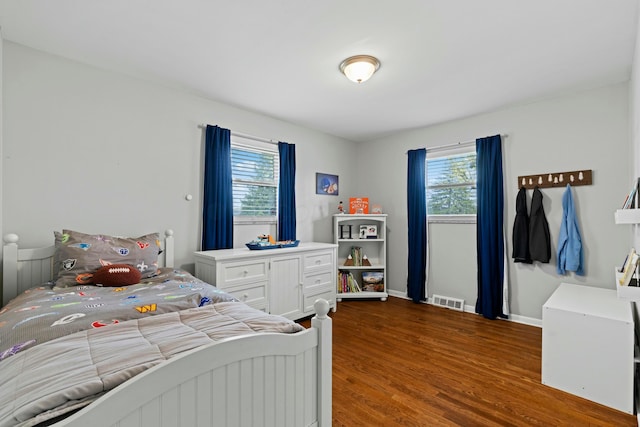 bedroom with dark wood-style flooring, visible vents, and baseboards