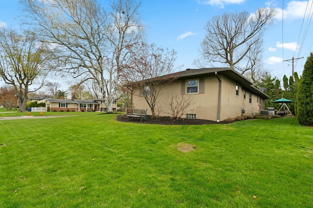view of side of property with stucco siding and a lawn