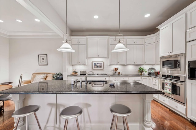 kitchen with pendant lighting, stainless steel appliances, white cabinetry, and dark stone counters