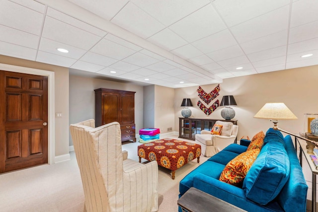 living room with a paneled ceiling and light colored carpet