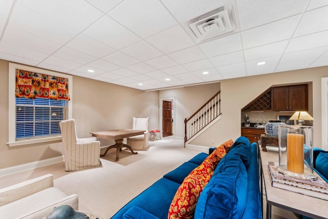 carpeted living room with a drop ceiling