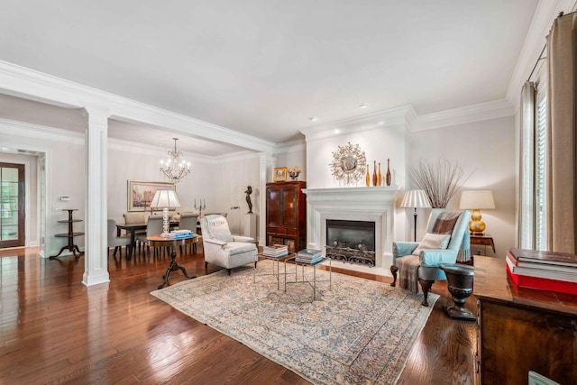 living room featuring hardwood / wood-style flooring, ornate columns, ornamental molding, and a notable chandelier