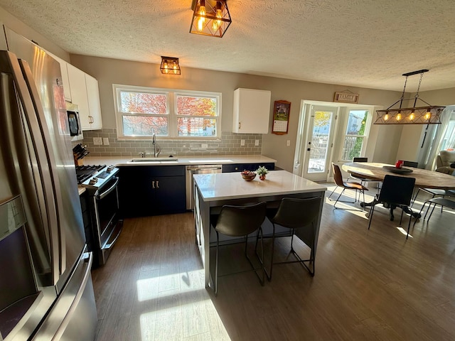 kitchen with plenty of natural light, a center island, hanging light fixtures, and appliances with stainless steel finishes