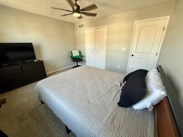 carpeted bedroom with ceiling fan, a closet, and a textured ceiling