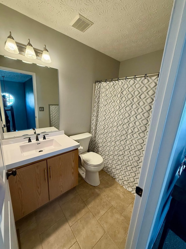 bathroom featuring tile patterned flooring, vanity, a textured ceiling, and toilet