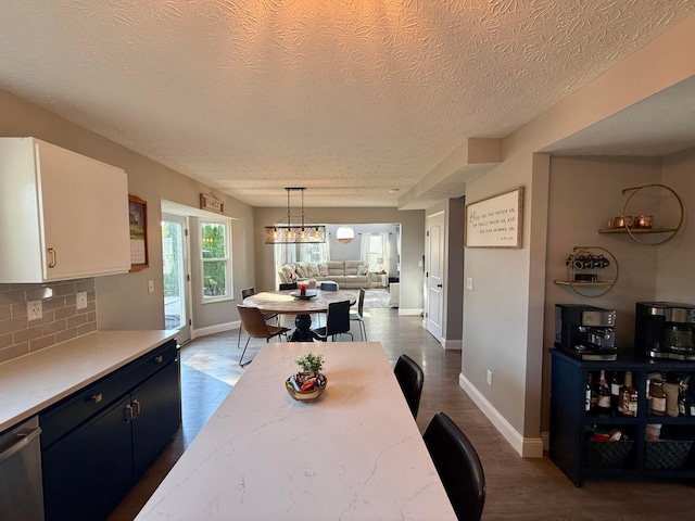 kitchen featuring pendant lighting, dishwasher, backsplash, white cabinets, and a textured ceiling