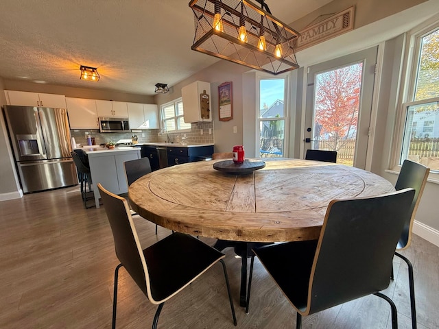 dining area with a textured ceiling, dark hardwood / wood-style flooring, and sink