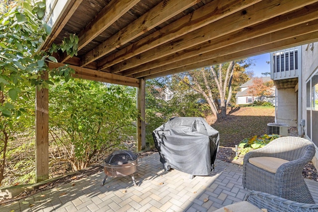 view of patio / terrace with a fire pit, cooling unit, and a grill