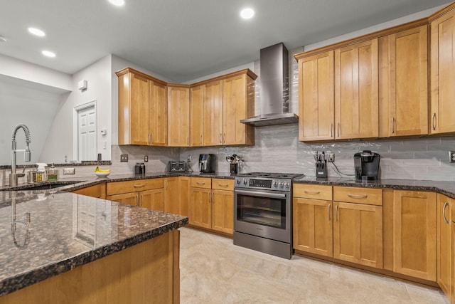 kitchen with backsplash, sink, wall chimney exhaust hood, dark stone countertops, and high end stove