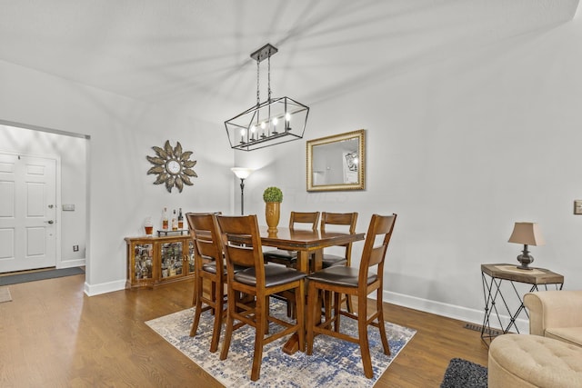 dining space featuring dark hardwood / wood-style flooring and an inviting chandelier