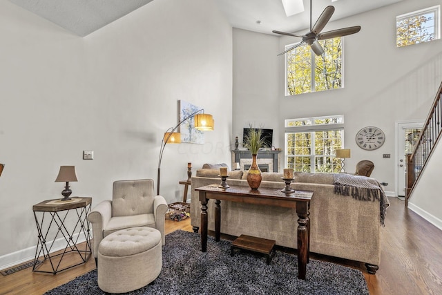 living room featuring ceiling fan, wood-type flooring, and a high ceiling