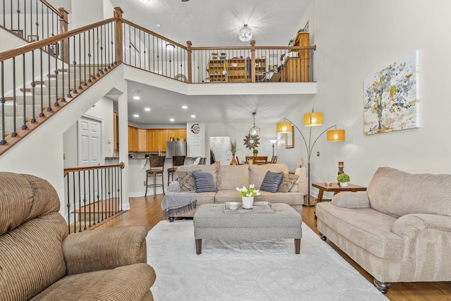 living room featuring light wood-type flooring and a towering ceiling