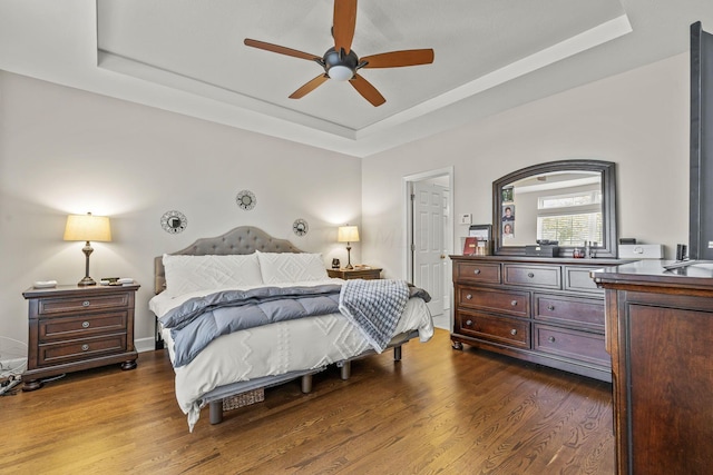 bedroom featuring a raised ceiling, ceiling fan, and dark wood-type flooring