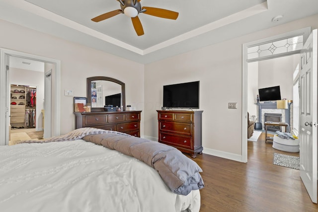 bedroom featuring ceiling fan, a raised ceiling, and wood-type flooring