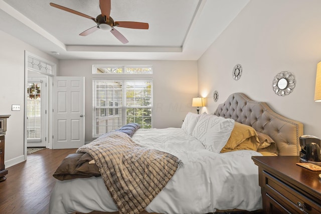 bedroom with a tray ceiling, ceiling fan, and dark hardwood / wood-style floors