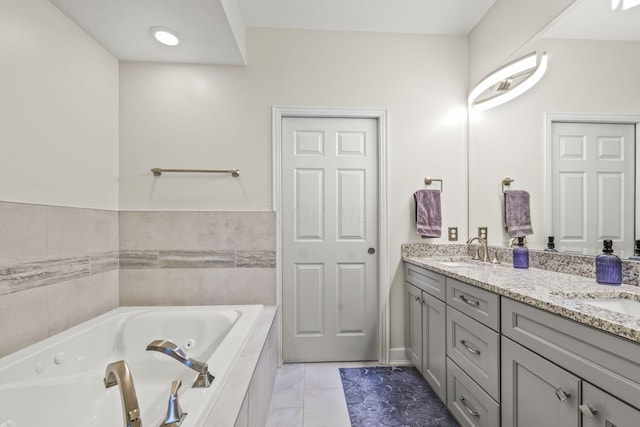 bathroom with tiled tub, tile patterned flooring, and vanity