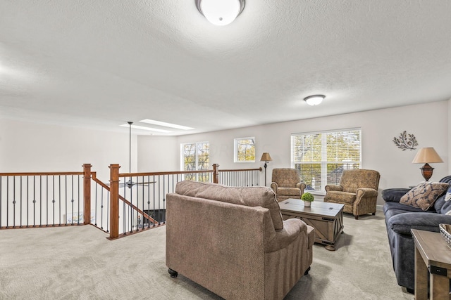 living room with a textured ceiling, plenty of natural light, light carpet, and a skylight