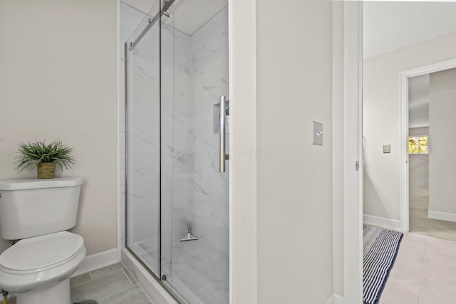 bathroom featuring tile patterned floors, a shower with door, and toilet