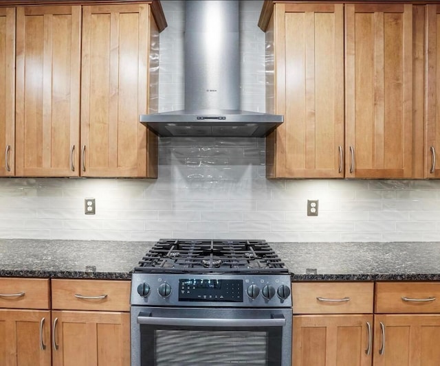 kitchen with decorative backsplash, stainless steel stove, dark stone countertops, and wall chimney range hood