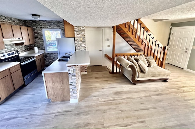 kitchen featuring decorative backsplash, range with electric cooktop, refrigerator, a textured ceiling, and sink