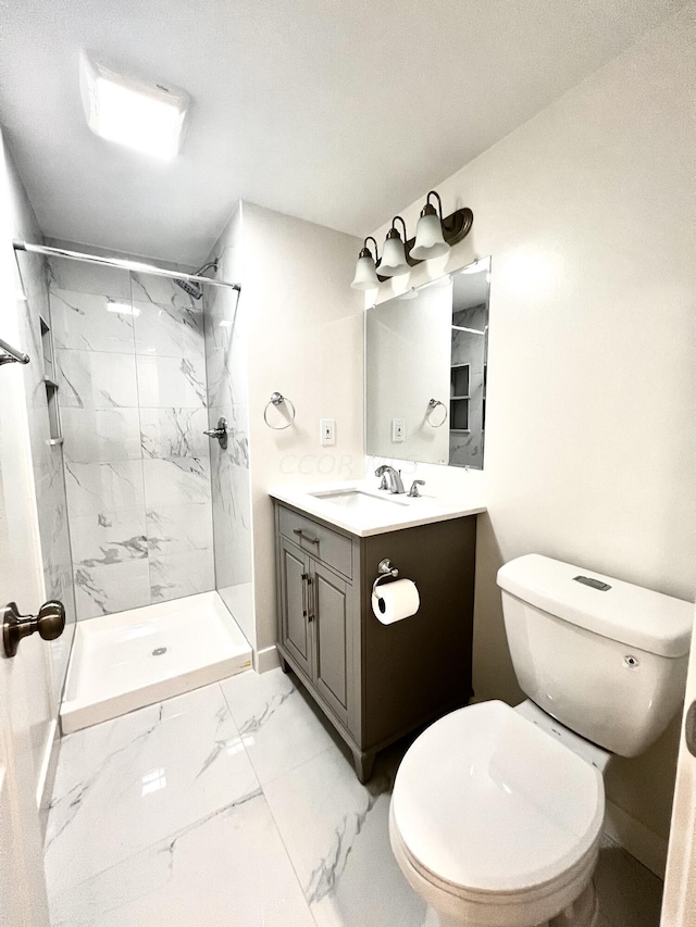 bathroom featuring a tile shower, vanity, and toilet