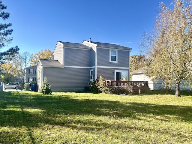 rear view of house featuring a wooden deck and a lawn