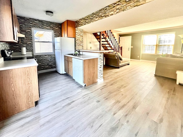 kitchen featuring a textured ceiling, white appliances, a healthy amount of sunlight, sink, and light hardwood / wood-style floors