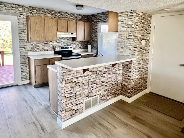 kitchen featuring stainless steel electric range, kitchen peninsula, and a textured ceiling